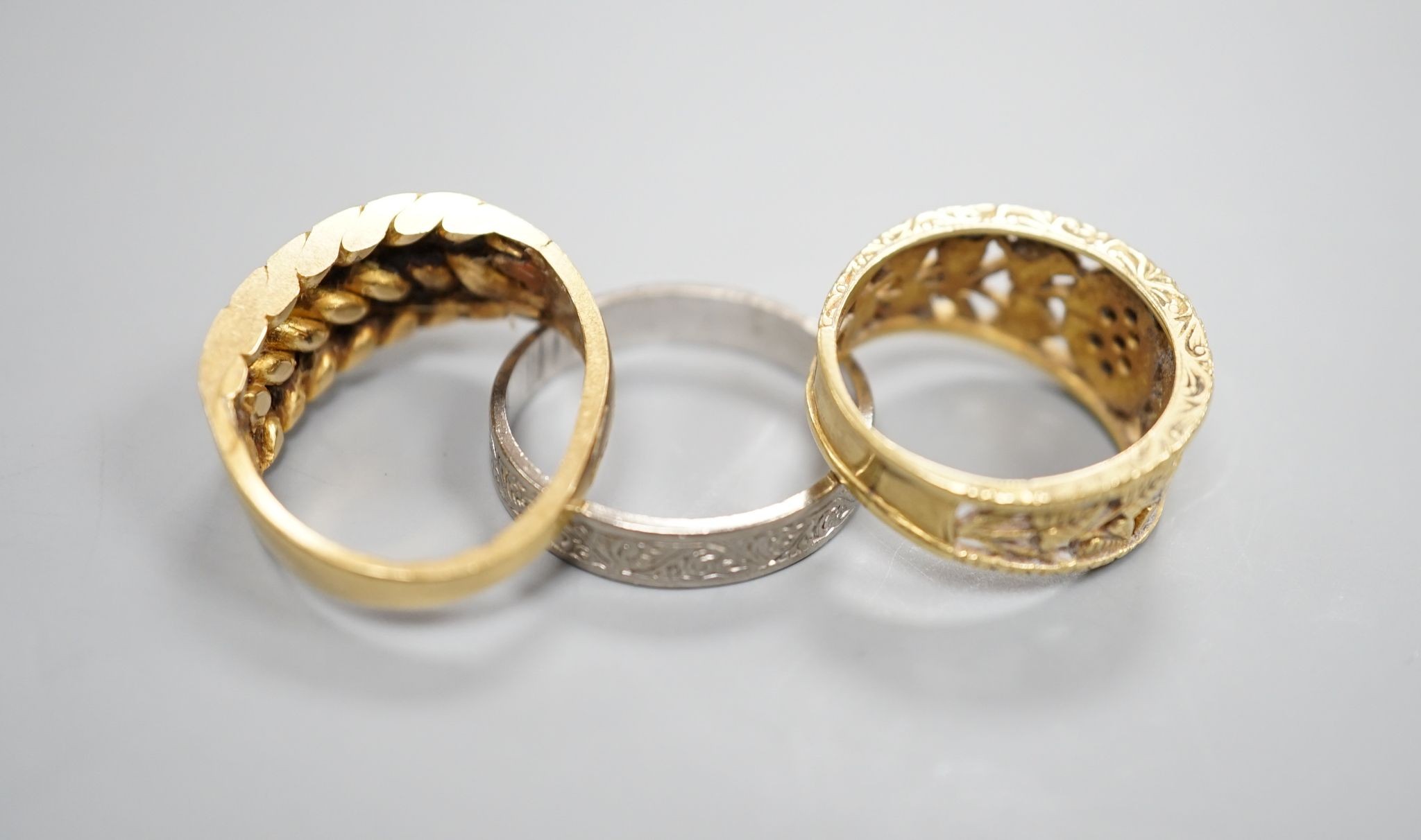 An engraved 18ct white gold wedding band, size P, and 18ct gold interwoven ring(a.f.) and a pierced yellow metal and diamond cluster ring